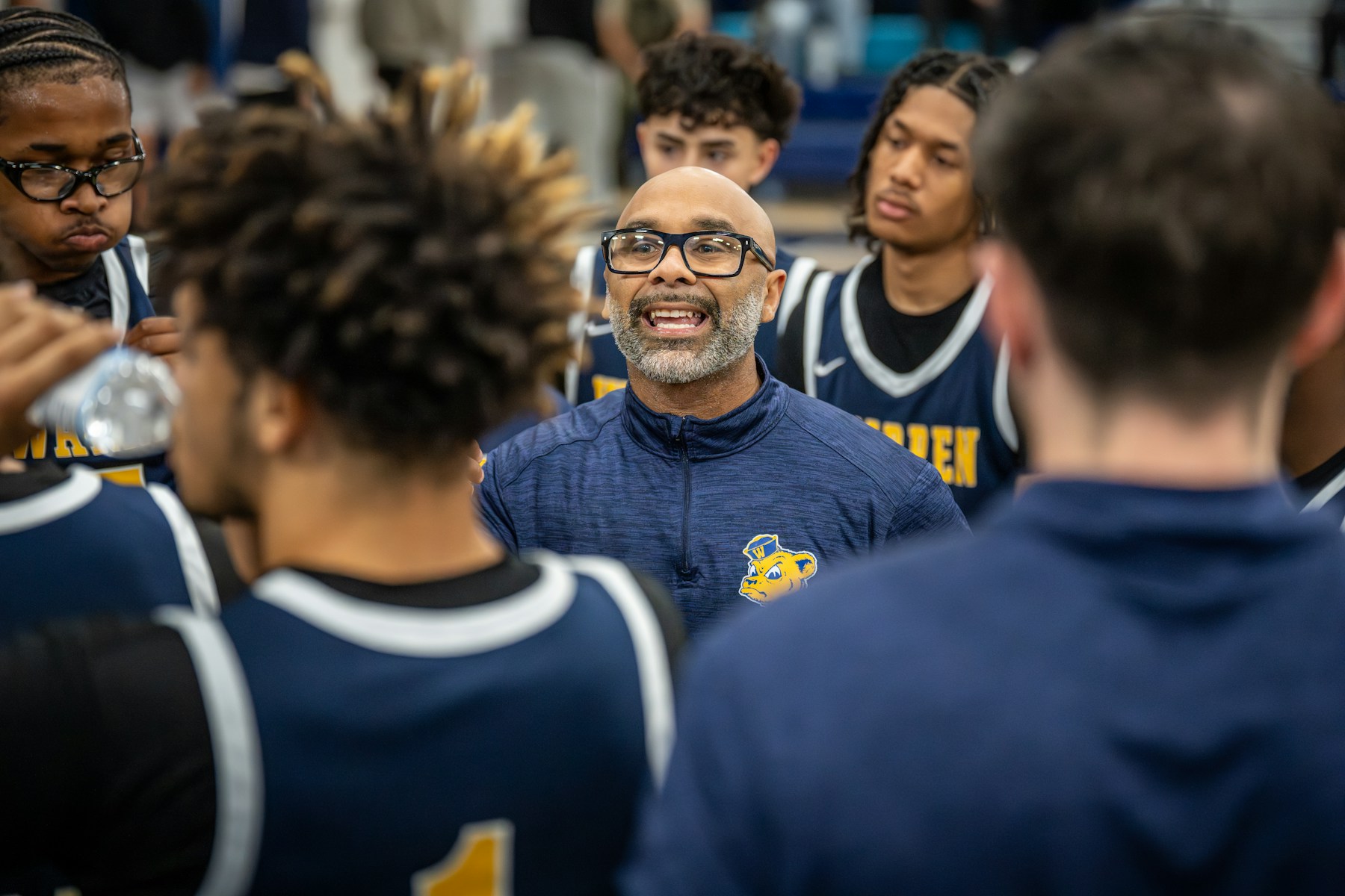 Coach giving instructions to basketball players during a huddle.